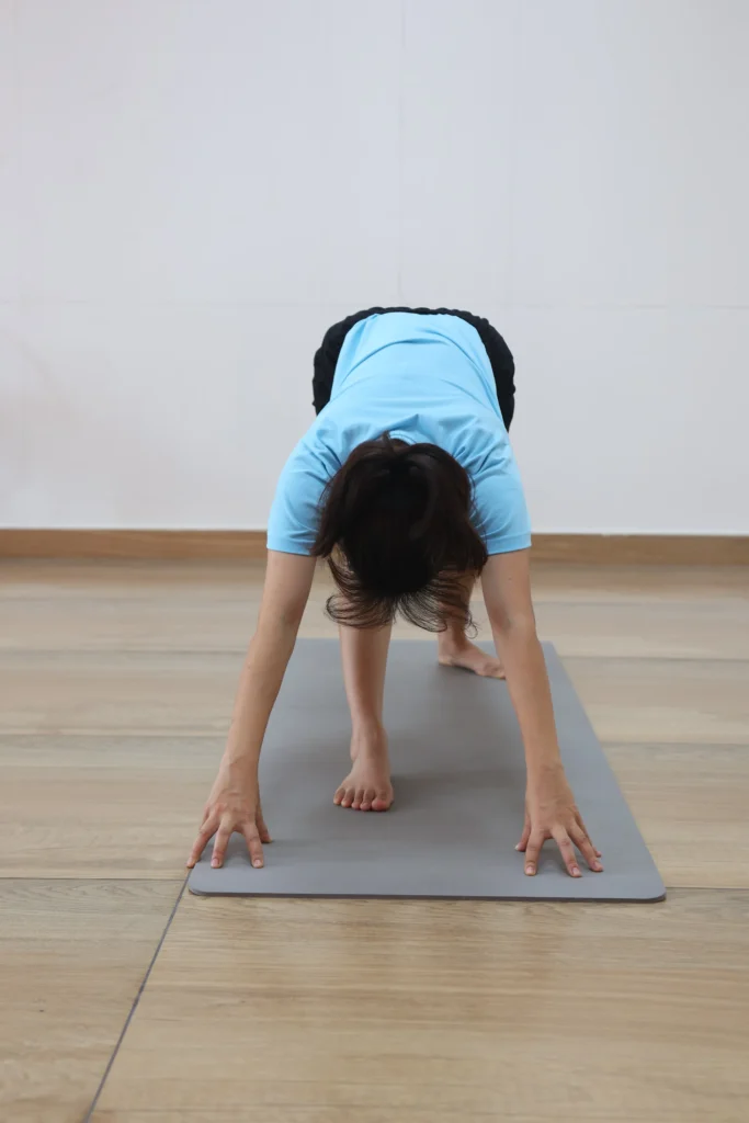 Yoga practitioner doing wall downward-facing dog stretch to release rounded shoulders and lengthen thoracic spine